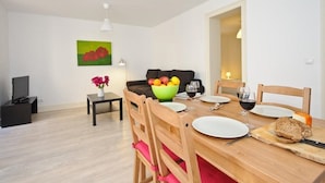 A dining area with a wooden table set for four, a bowl of fruit, and a loaf of bread on the table. - Portugal Ways Lisbon City Apartments (Lisbon)