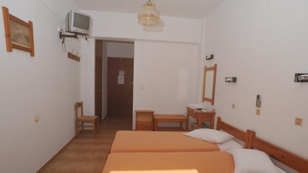 A small, clean room with two beds, a desk, a chair, a television, and a door leading to another room. - Castelli (Patmos)
