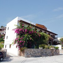 Un hotel con fachada blanca, pared de piedra y un letrero que dice 'CASTELI HOTEL'.