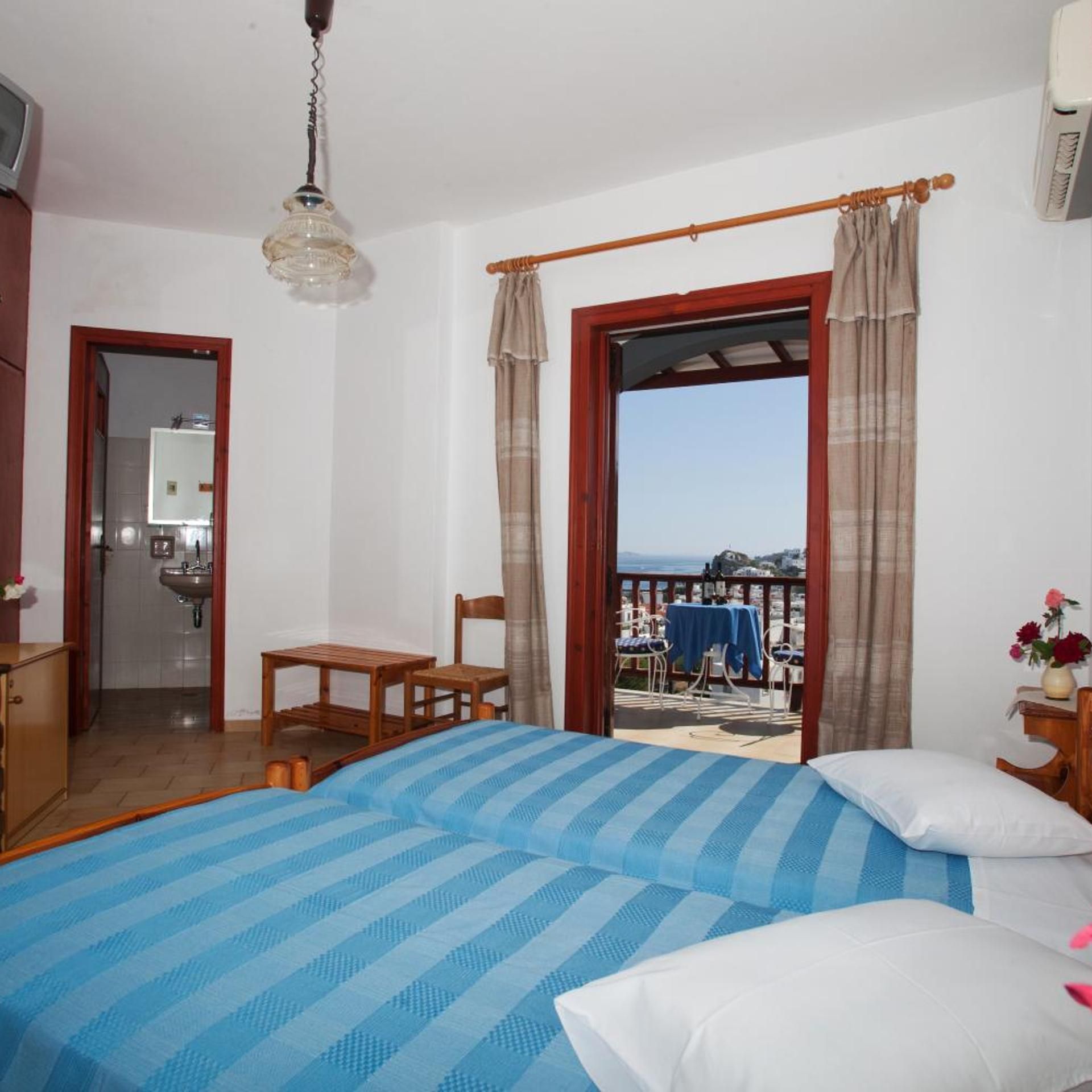 A bedroom with a bed, a chair, a table, a sink, and a view of the sea.