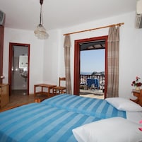 Un dormitorio con cama, una silla, una mesa, un lavamanos y vistas al mar.