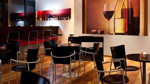 A modern bar area with a wine display and seating. - Olympic Village (Archaia Olympia)