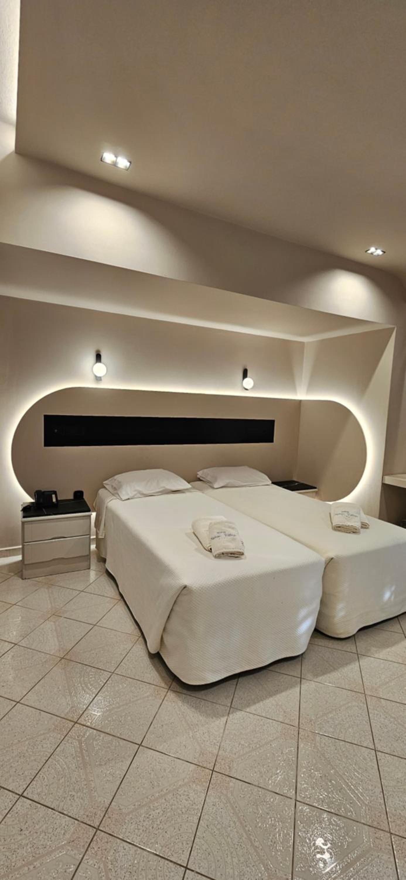 Camera d'hotel moderna con un ampio letto, comodini e un design del soffitto curvo.