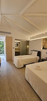 Habitación de hotel moderna con dos camas, un baño con espejo y vistas a zonas verdes.
