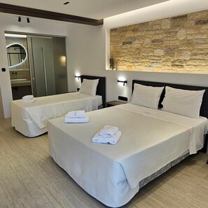 A hotel room with two beds, a stone wall, and a modern bathroom. - Olympic Village (Archaia Olympia)