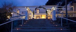 Un bâtiment doté d’une entrée imposante, d’un escalier menant aux portes principales et d’un balcon agrémenté de balustrades.