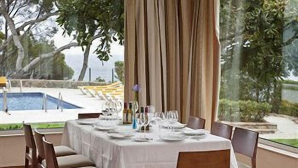 Mesa de comedor lista para seis personas, con vistas a una piscina y follaje.
