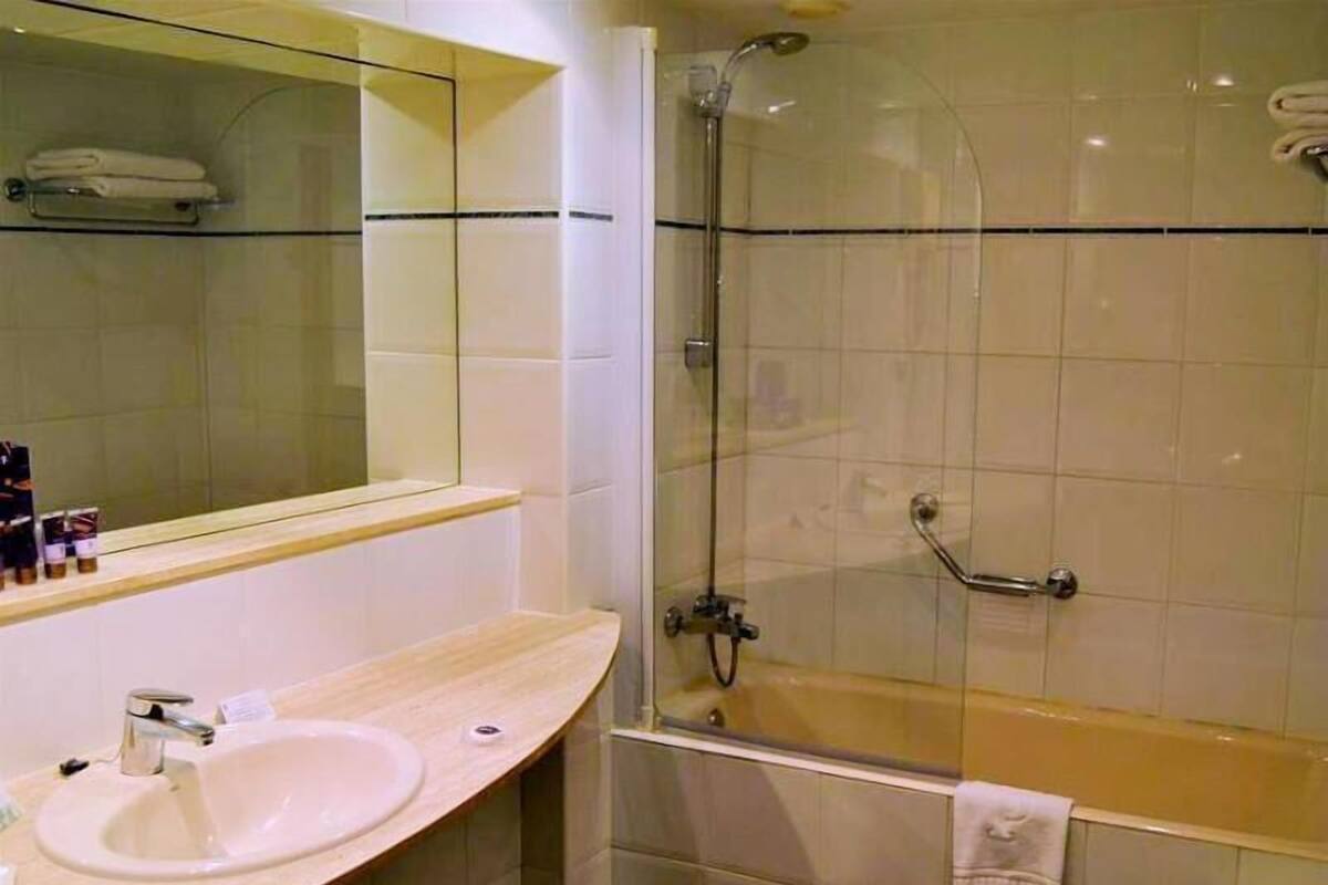A bathroom with a sink, mirror, shower, and bathtub.