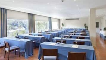 Een vergaderzaal met tafels en stoelen, grote ramen en uitzicht op de omgeving.