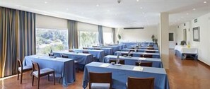 Une salle de conférence équipée de tables et de chaises, de grandes fenêtres et offrant une vue sur l’extérieur.