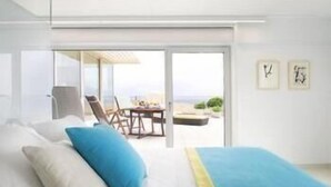 Una habitación de hotel moderna con cama, vistas a la playa y un comedor.