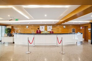 A reception desk with two staff members, a clock, and a bulletin board. - Golden Sands Hotel Apartments (Dubai)