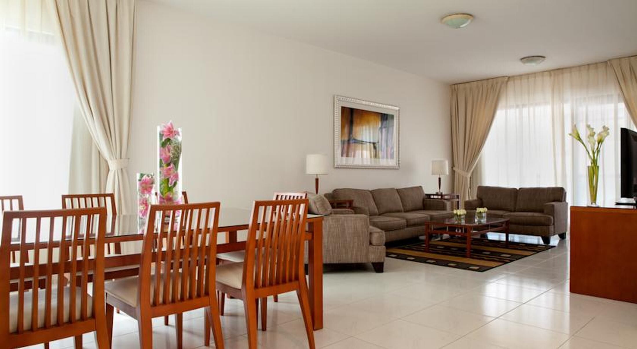 A modern living room with a sofa set, wooden chairs, a coffee table, and a TV.