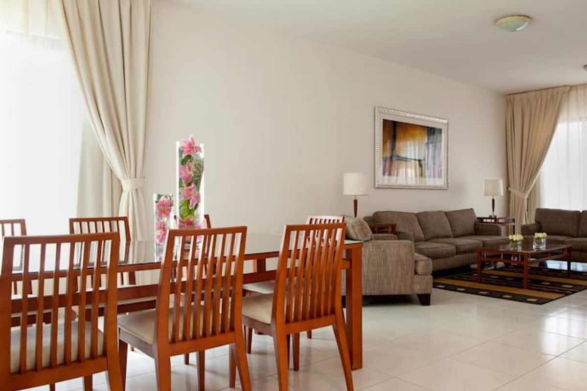 A modern living room with a sofa set, wooden chairs, a coffee table, and a TV.