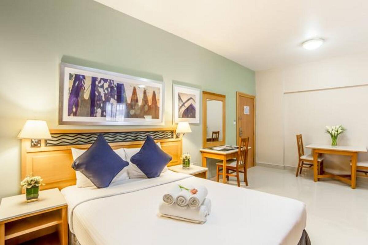A hotel room with a bed, two nightstands, a desk, and a chair.