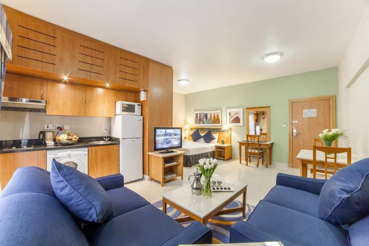 A compact living space with a kitchenette, a sofa set, a dining area, and a TV.