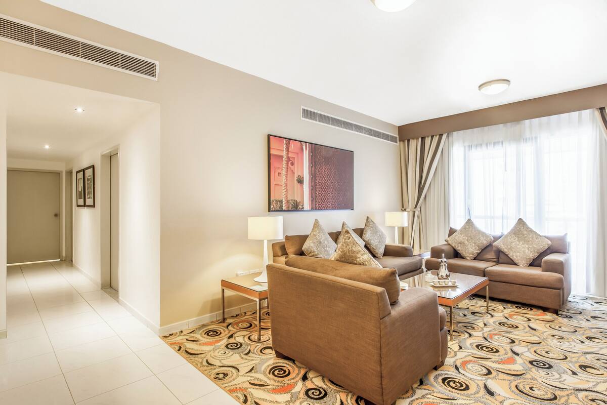 A modern living room with two sofas, a coffee table, and a patterned rug.