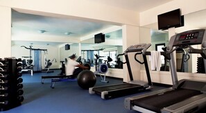 Un gimnasio con cintas de correr, pelotas de ejercicio y máquinas de pesas.