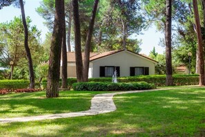 A house with a stone pathway leading to a door, surrounded by trees and a well-maintained lawn. - Village Galijot Plava Laguna (Porec)