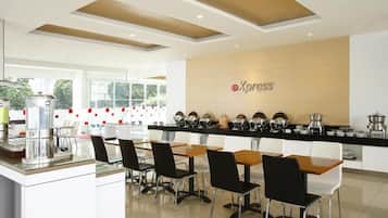 A modern dining area with a long counter, multiple chairs, and a coffee machine.