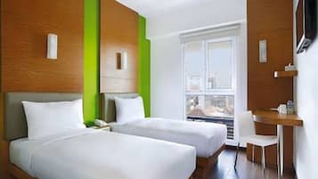 Ett hotellrum med två sängar, ett skrivbord, en stol, en TV och ett fönster.