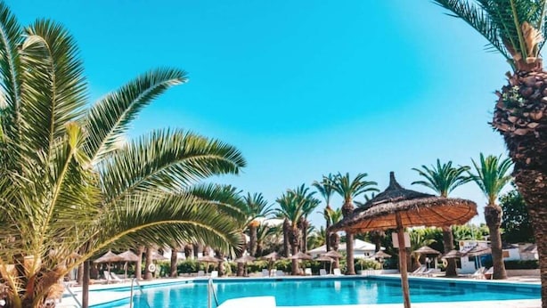 A pool area with palm trees, lounge chairs, and thatched umbrellas. - Agate Kanta Garden Resort (Port El Kantaoui)