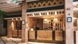 A reception area with a check-in counter, framed pictures on the wall, and a tiled floor. - Agate Kanta Garden Resort (Port El Kantaoui)