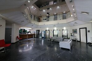 Un vestíbulo amplio con mostrador de recepción, zona de estar y un entrepiso.
