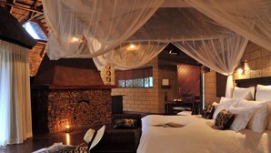 Um quarto com cama, parede de pedra, lareira e janela.