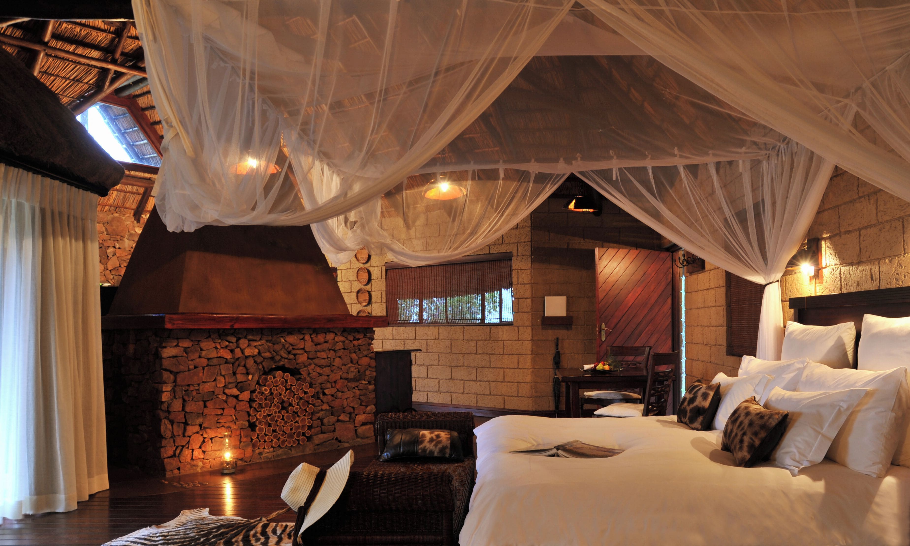 A room with a bed, a stone wall, a fireplace, and a window.