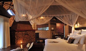 A room with a bed, a stone wall, a fireplace, and a window. - Zwahili Game Lodge (Modimolle)