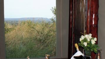 Ein Badezimmer mit einem großen Fenster, das Blick auf eine grüne Landschaft und ferne Hügel gewährt.