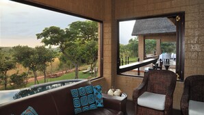 A room with a view of a natural landscape, a pool, and outdoor seating.