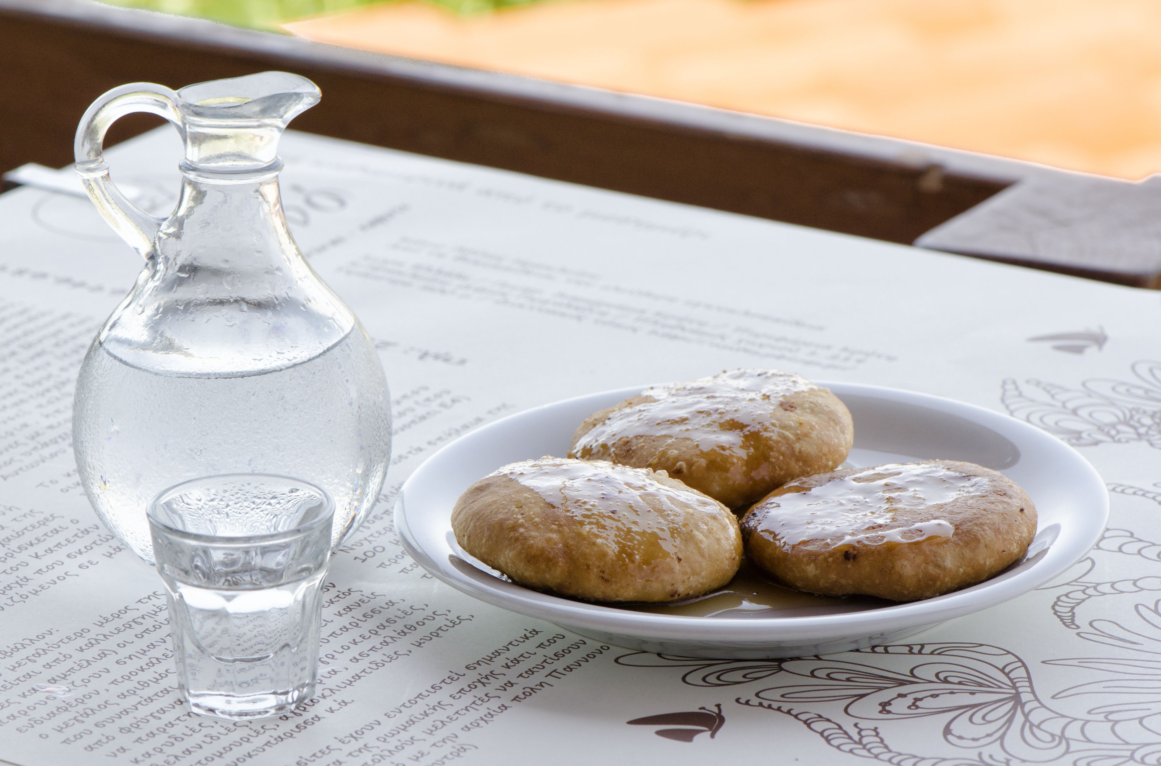 A table with a pitcher of water, a plate of pastries, and a menu.