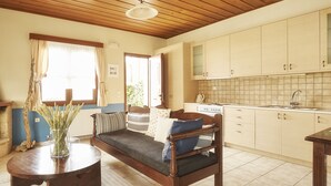 A cozy living room with a fireplace, a sofa, and a dining table. - Earino (Heraklion)