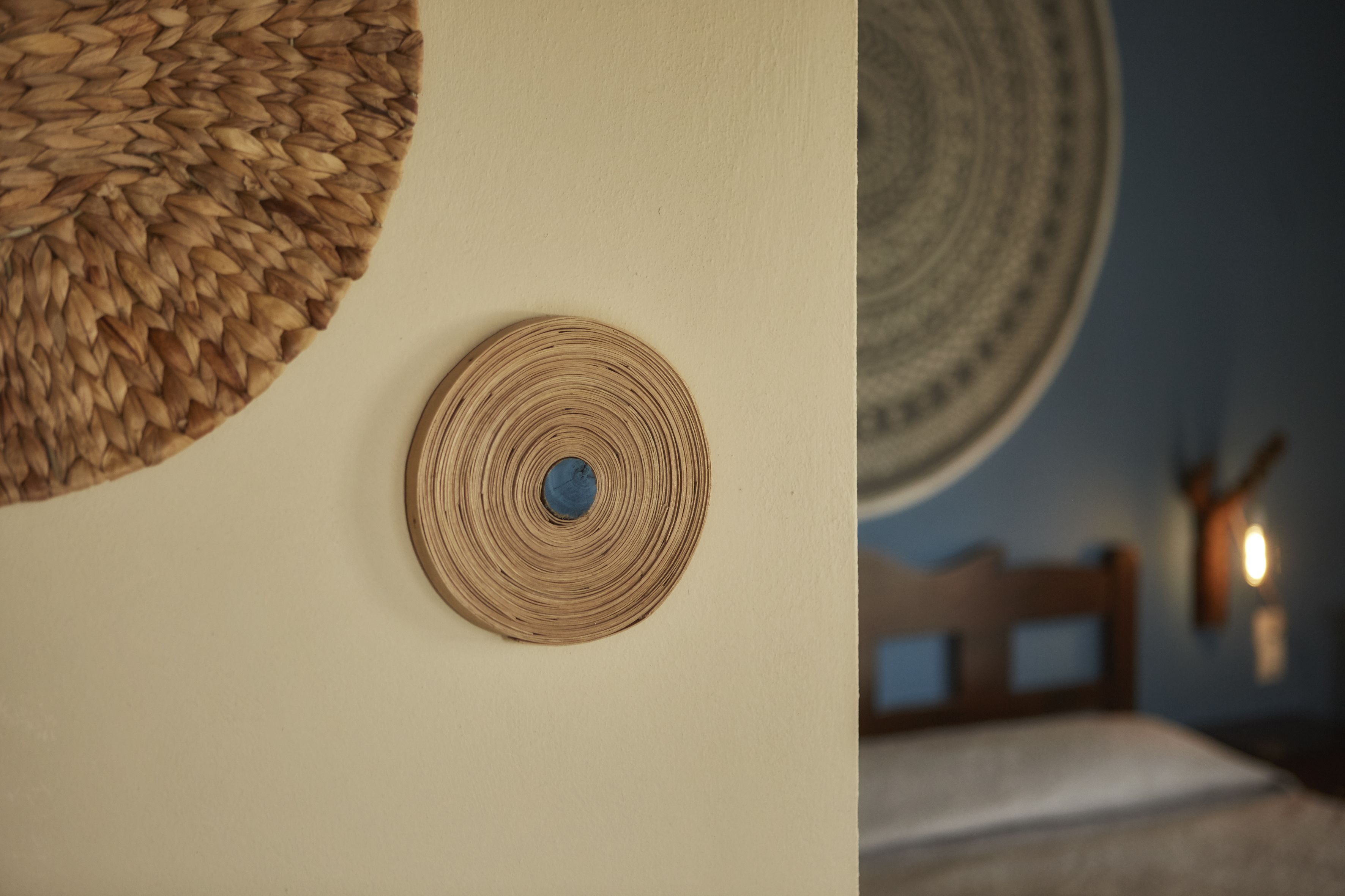 Una habitación con una cama, un tapiz de pared tejido y una decoración circular en la pared.