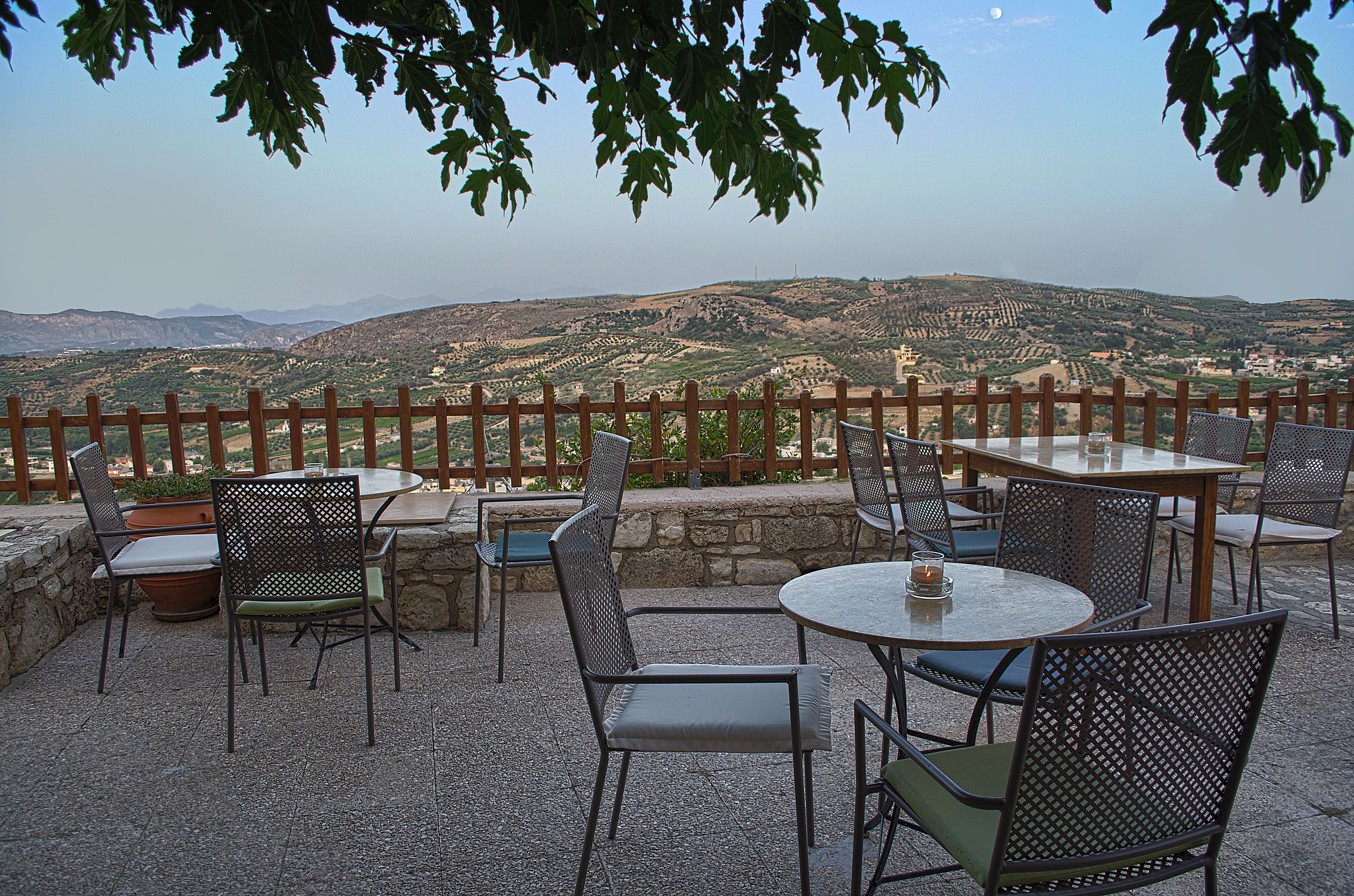 Un patio al aire libre con mesas y sillas, con vistas a un paisaje montañoso.