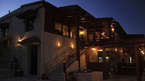 A two-story building with a stone facade, a wooden staircase, and outdoor seating area. - Earino (Heraklion)