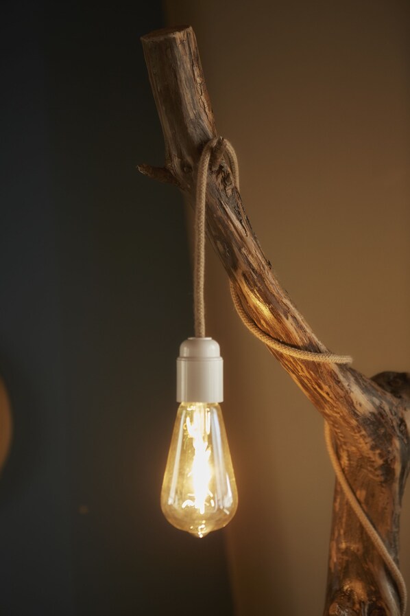 A light bulb hanging from a twisted branch.