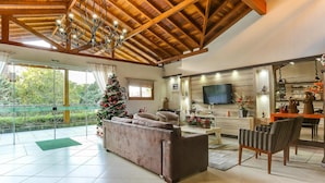 A spacious living area with a wooden ceiling, a Christmas tree, a sofa, and a television. - Zermatt Hotel (Gramado)