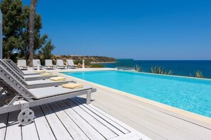 A poolside area with lounge chairs and a clear view of the sea.