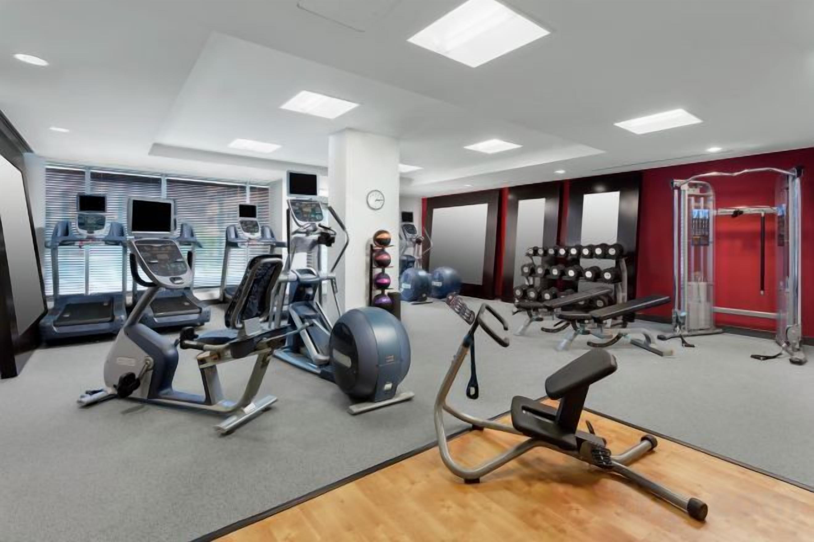 Academia com máquinas de cardio, equipamentos de musculação e diversos bolas de exercício.