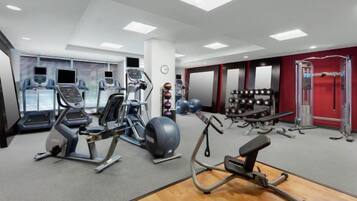 Academia com máquinas de cardio, equipamentos de musculação e diversos bolas de exercício.