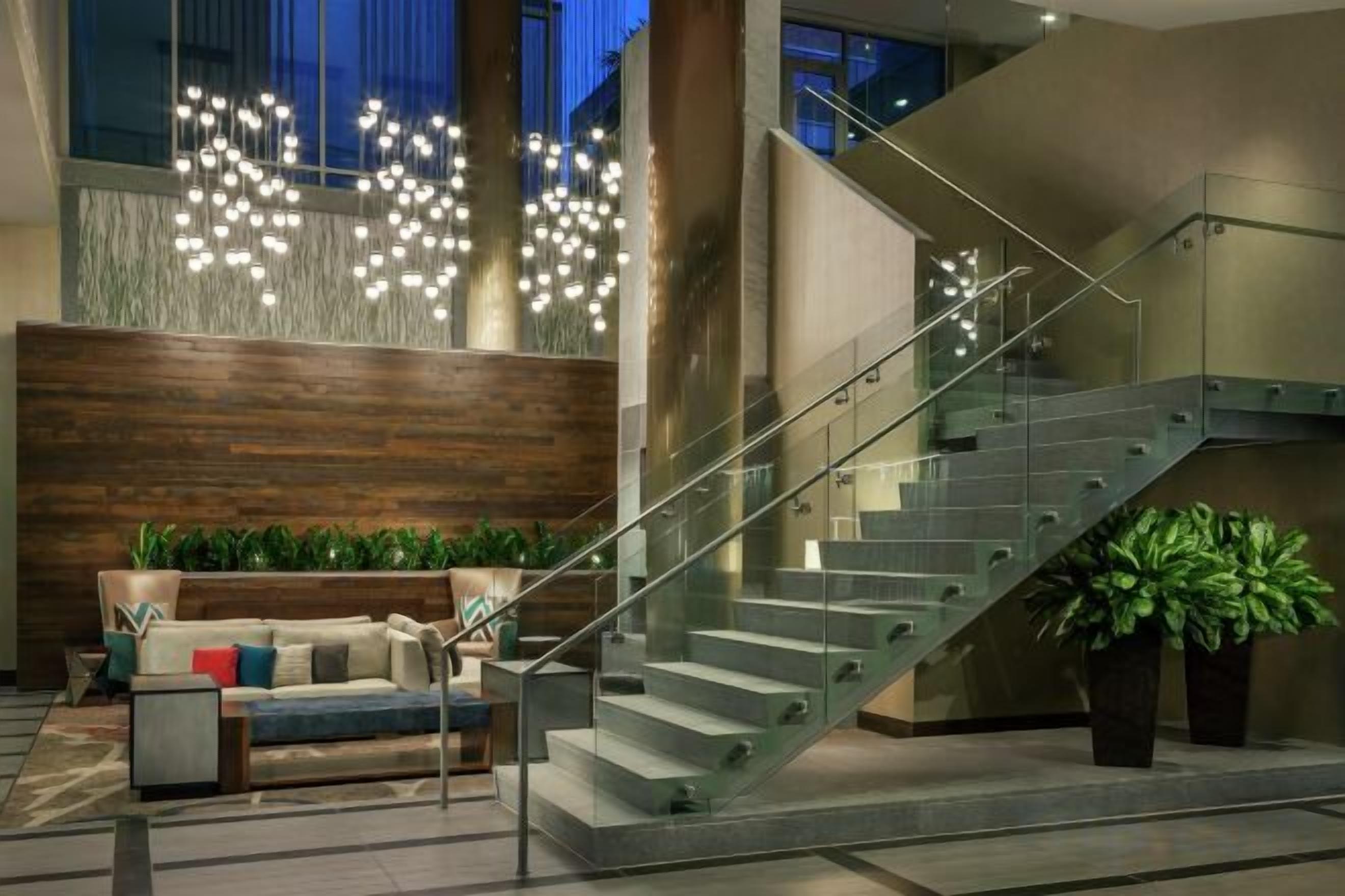 A modern interior with a staircase, seating area, and decorative lighting.