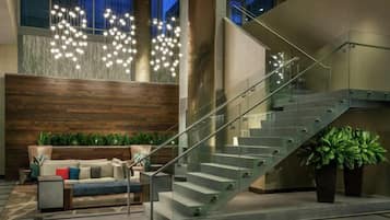 A modern interior with a staircase, seating area, and decorative lighting.