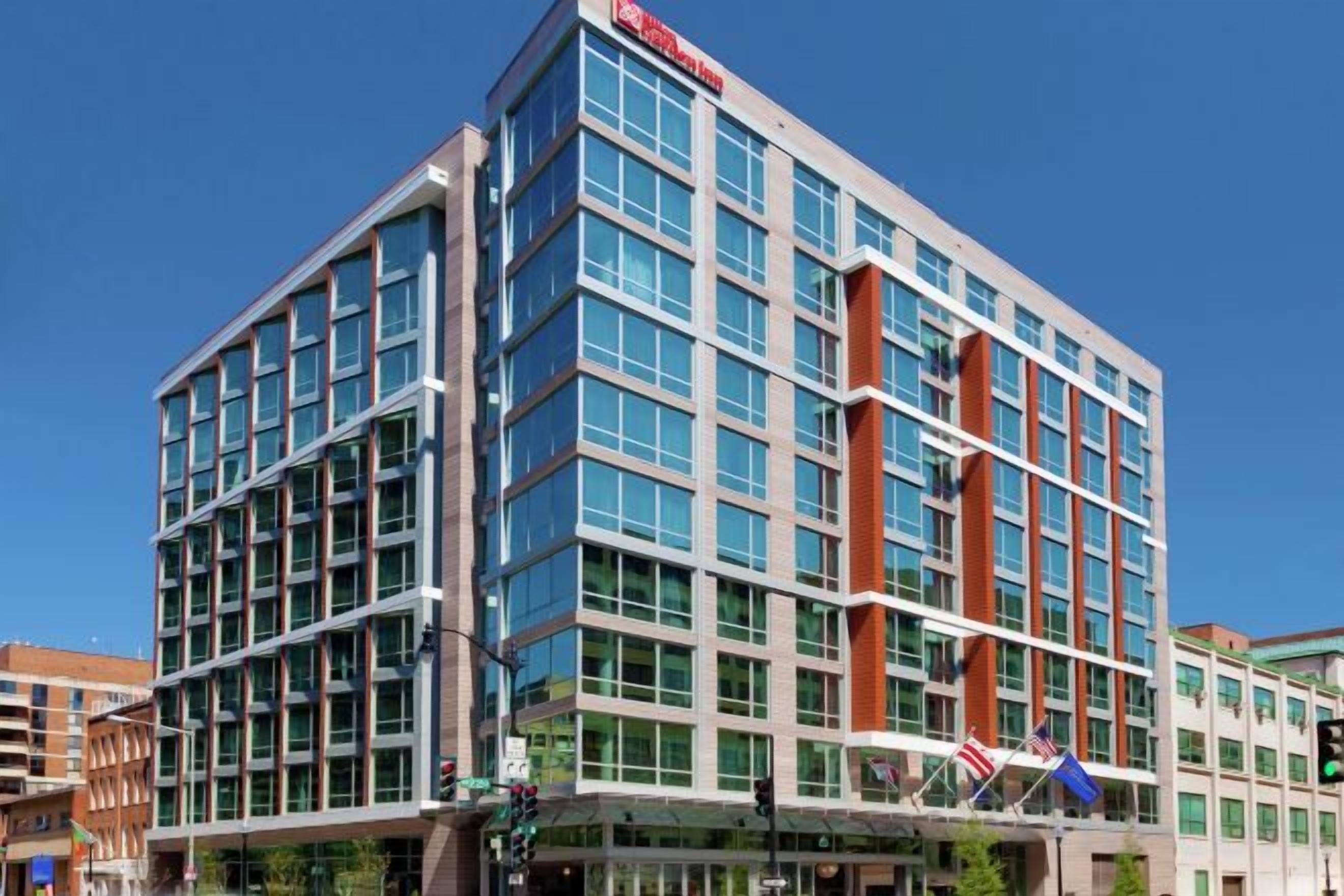 A multi-story hotel with a modern glass facade, a prominent entrance with a canopy, and a flag on the corner.