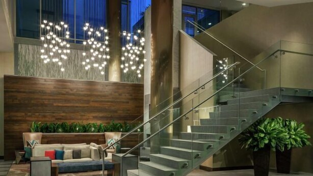 En moderne lobby med trappe, sofa og plantekasser.