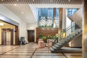 Un moderno vestíbulo de hotel con una escalera, zona de estar y un mostrador de recepción.