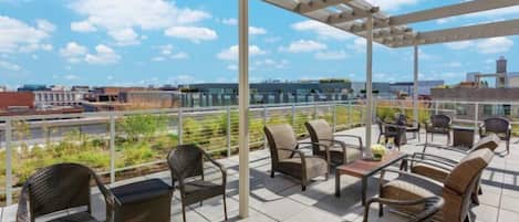 Un patio al aire libre con mobiliario de mimbre y vistas a la ciudad.