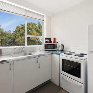 A modern kitchen with a stainless steel sink, a microwave, a kettle, and a stove. - The Parnell Hotel and Conference Centre (Auckland)